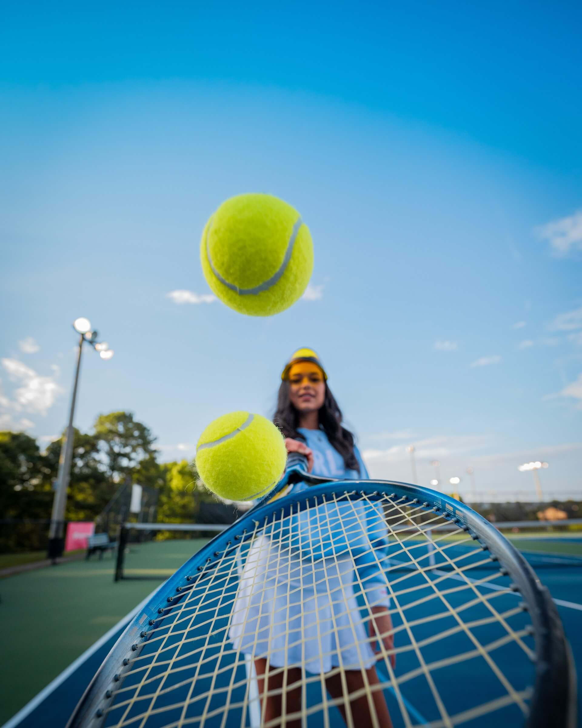 woman holding tennis racquet and bouncing tennis balls